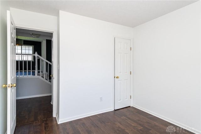 spare room with baseboards and dark wood-style floors