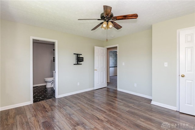 unfurnished bedroom with wood finished floors, baseboards, a textured ceiling, a ceiling fan, and ensuite bath