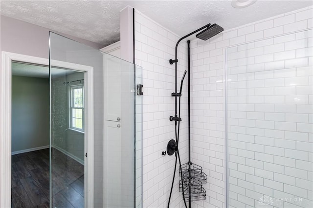 full bathroom featuring baseboards, a textured ceiling, wood finished floors, and a shower stall