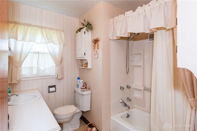 bathroom featuring toilet, a sink, and shower / tub combo with curtain