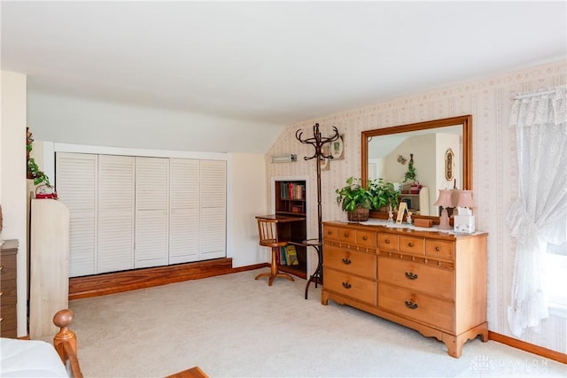 bedroom with a closet, lofted ceiling, light carpet, baseboards, and wallpapered walls