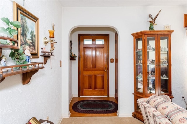 interior space with baseboards, arched walkways, and a textured wall