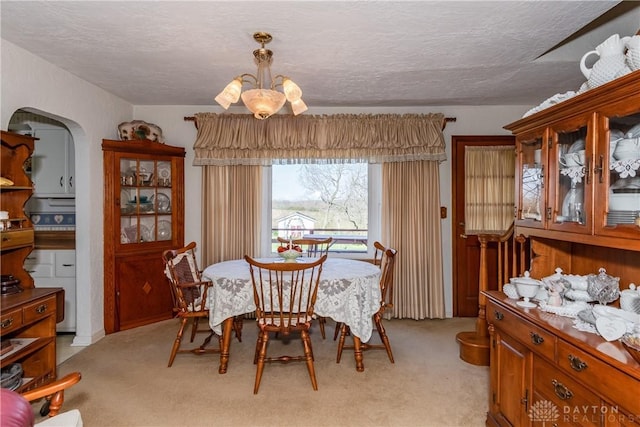 dining area with arched walkways, a textured ceiling, a notable chandelier, and light carpet