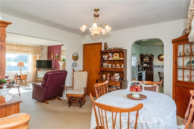 dining area featuring arched walkways, a notable chandelier, and carpet flooring