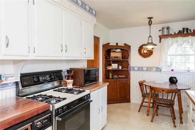 kitchen with white cabinets, hanging light fixtures, black microwave, gas stove, and wallpapered walls