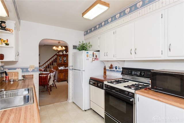 kitchen with arched walkways, open shelves, white cabinets, wood counters, and white appliances
