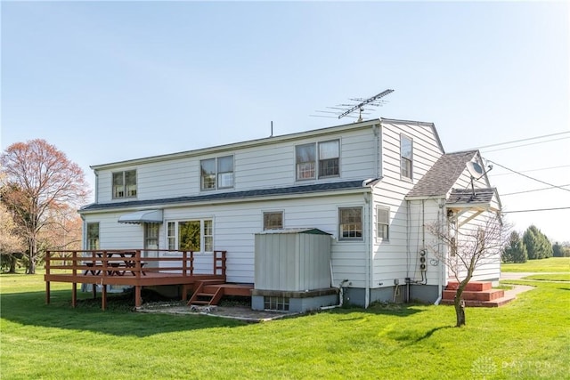 back of house with roof with shingles, a wooden deck, and a yard