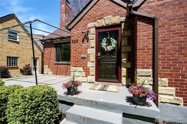 entrance to property featuring brick siding and a chimney