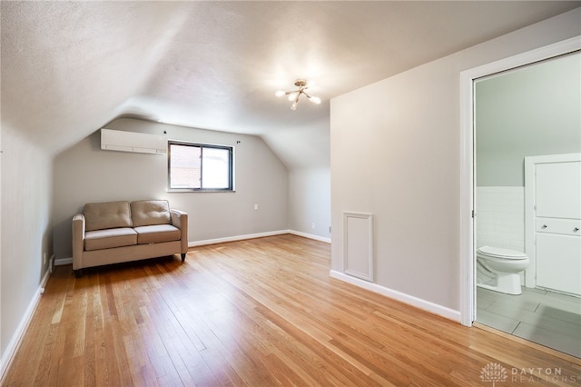 additional living space featuring baseboards, a wall unit AC, hardwood / wood-style flooring, and lofted ceiling