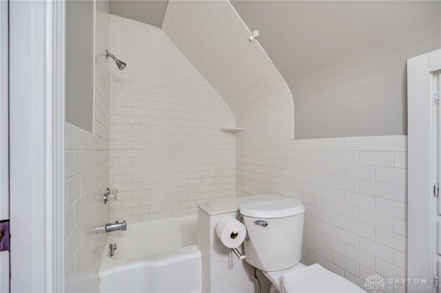 full bathroom with bathing tub / shower combination, toilet, and tile walls
