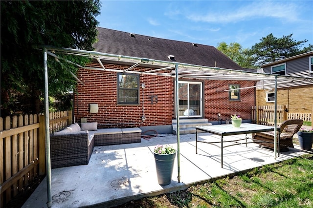 rear view of house with brick siding, fence, a patio, and an outdoor hangout area