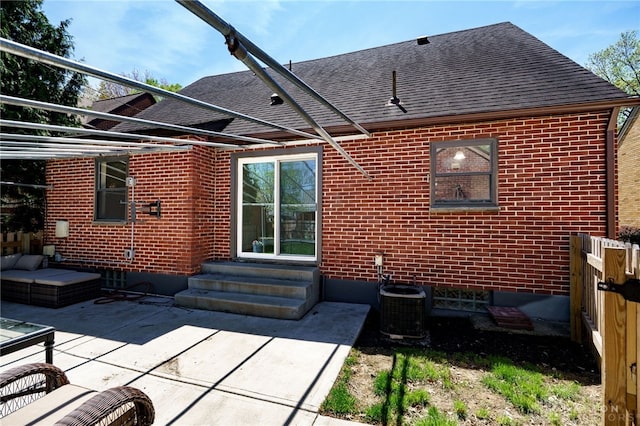 rear view of property featuring roof with shingles, a patio area, brick siding, cooling unit, and entry steps