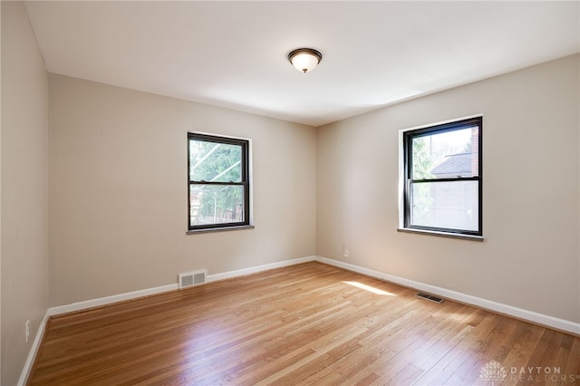 empty room with baseboards, light wood finished floors, and visible vents