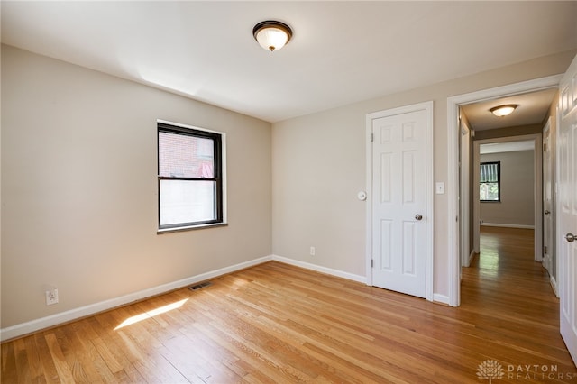 spare room featuring baseboards, visible vents, and light wood-type flooring