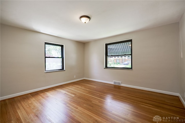 unfurnished room featuring baseboards, wood finished floors, and visible vents