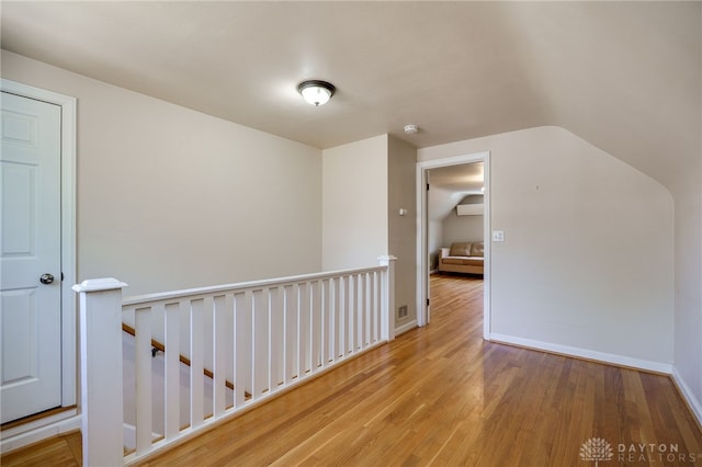 interior space featuring baseboards, wood finished floors, and lofted ceiling