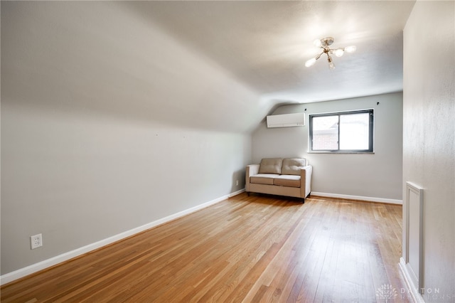 unfurnished room featuring lofted ceiling, light wood-style floors, baseboards, a wall unit AC, and a notable chandelier