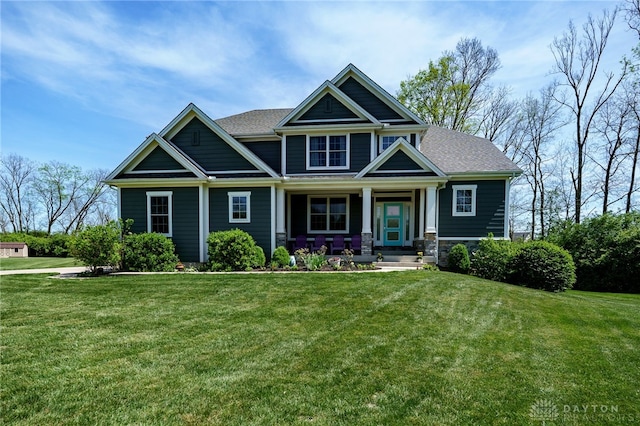 craftsman-style home featuring covered porch, stone siding, and a front yard