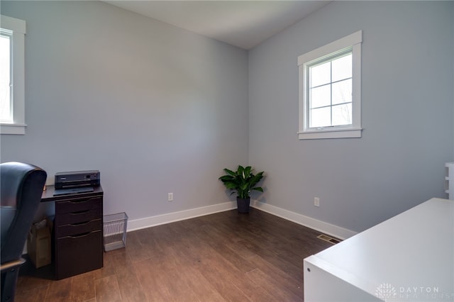 unfurnished office with baseboards, visible vents, and dark wood-style floors