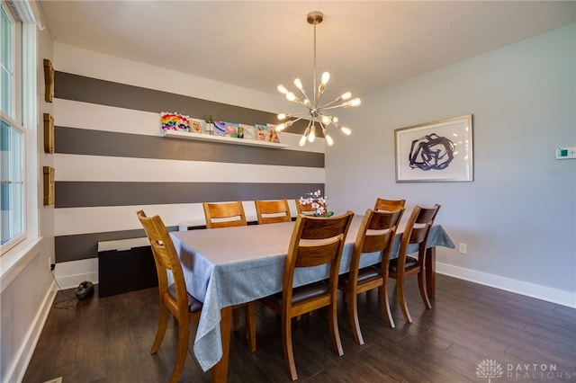 dining space featuring baseboards, wood finished floors, and a notable chandelier
