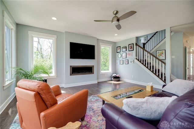 living room with a ceiling fan, a wealth of natural light, wood finished floors, and stairway