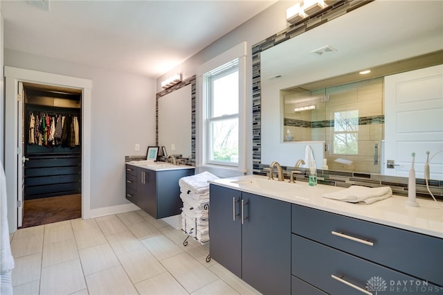 bathroom featuring visible vents, a shower stall, two vanities, a sink, and a spacious closet