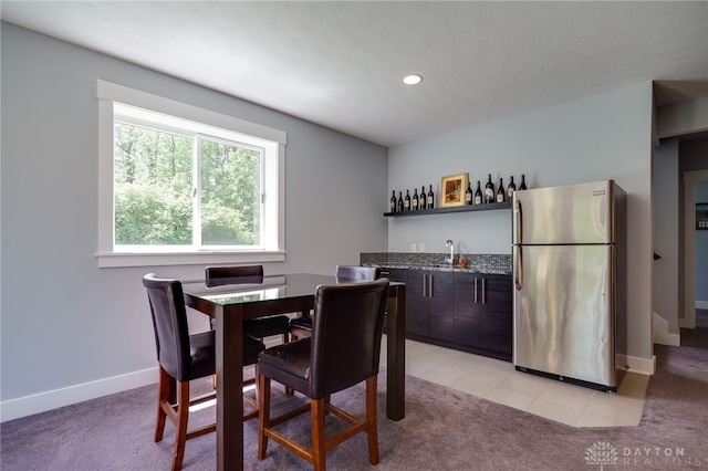 dining room featuring baseboards, recessed lighting, wet bar, and light colored carpet