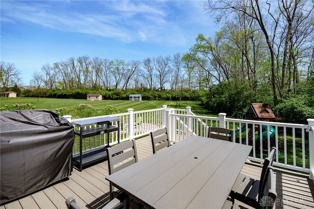 deck featuring a yard, an outbuilding, and outdoor dining space