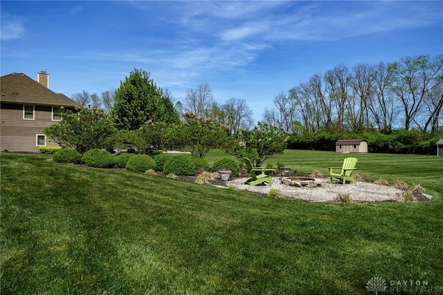 view of yard featuring an outbuilding, a storage unit, and an outdoor fire pit