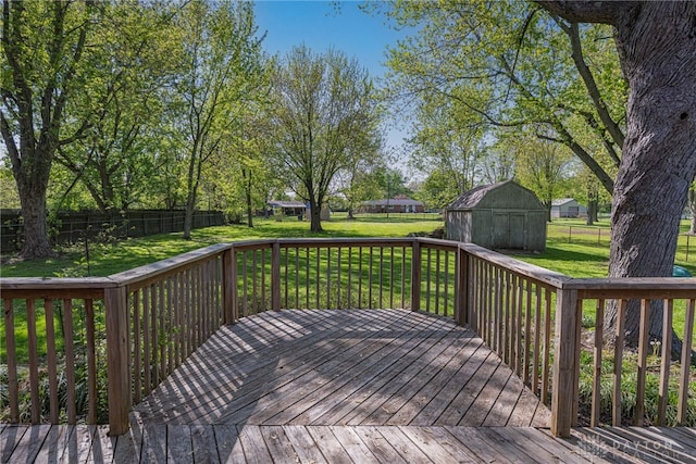 wooden deck with a lawn, an outbuilding, a shed, and a fenced backyard