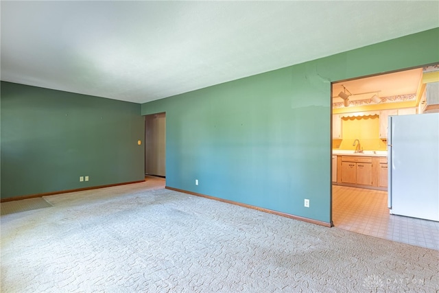 spare room with baseboards and light carpet