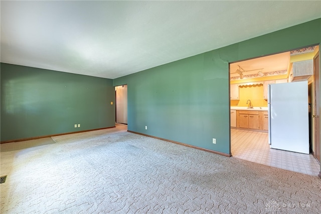 unfurnished room featuring a sink, baseboards, and light colored carpet