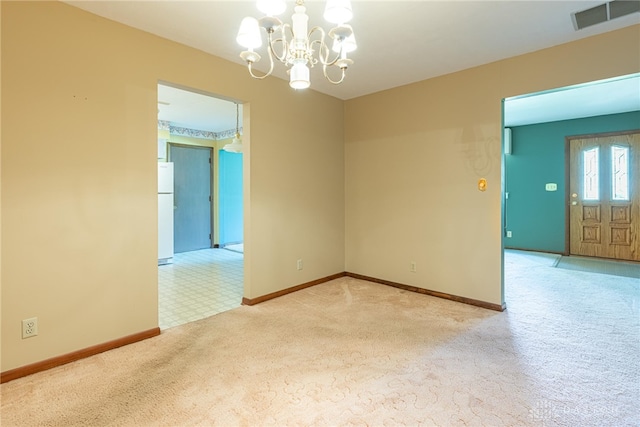 spare room with a chandelier, baseboards, visible vents, and carpet