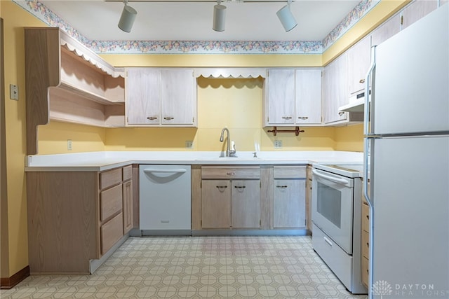 kitchen with a sink, white appliances, light countertops, light floors, and under cabinet range hood