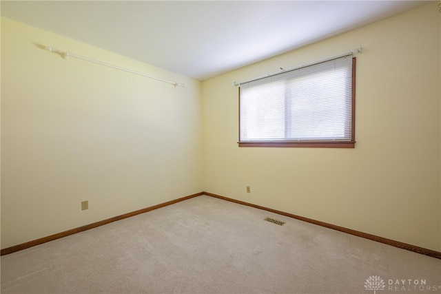 carpeted spare room featuring baseboards and visible vents