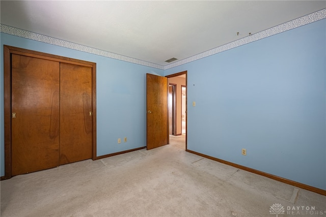 unfurnished bedroom with baseboards, light carpet, a closet, and visible vents