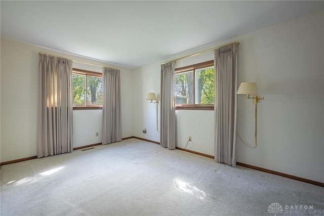 carpeted empty room featuring baseboards and visible vents