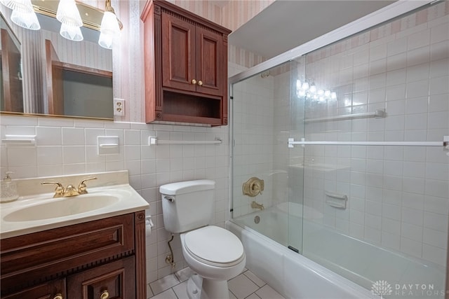 bathroom featuring tile patterned flooring, vanity, toilet, wallpapered walls, and bath / shower combo with glass door