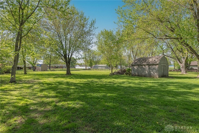 view of yard featuring a storage shed, fence, and an outdoor structure