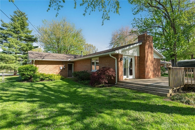 back of house featuring a wooden deck, fence, a chimney, brick siding, and a yard