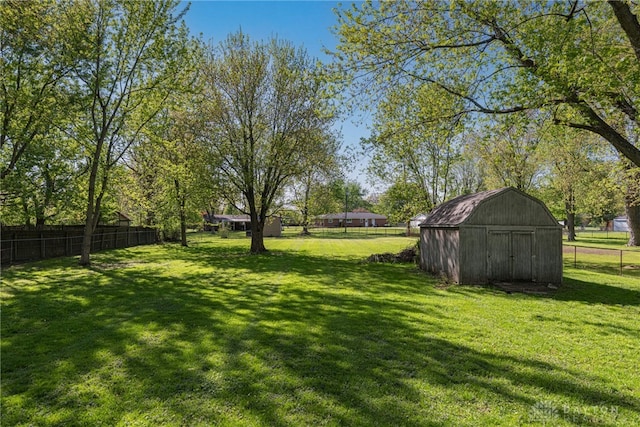 view of yard featuring a storage shed, fence, and an outbuilding