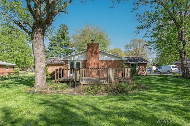 back of property featuring a lawn, a wooden deck, a chimney, and brick siding