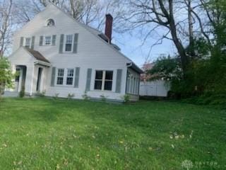 rear view of property with a yard and a chimney