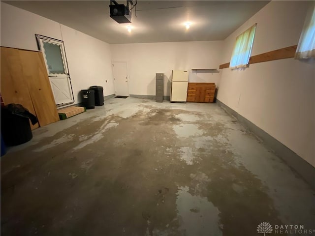 garage with a garage door opener and freestanding refrigerator