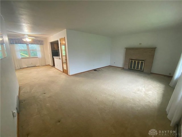 unfurnished living room with carpet flooring, ceiling fan, baseboards, and a fireplace