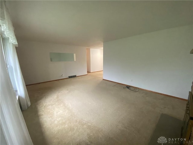 interior space with baseboards, visible vents, and light carpet