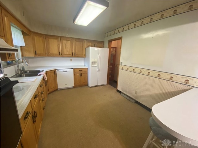 kitchen featuring brown cabinetry, a sink, light countertops, light carpet, and white appliances
