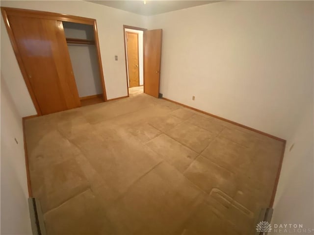 unfurnished bedroom with a closet and baseboards