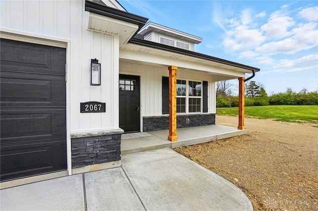 2067 Pine Forest Dr, Miamisburg, OH 45342 - view of exterior entry featuring covered porch, stone siding, board and batten siding, and a garage