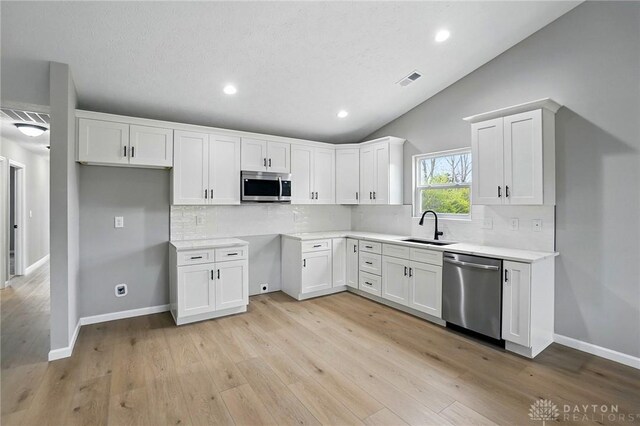 2067 Pine Forest Dr, Miamisburg, OH 45342 - kitchen featuring stainless steel appliances, a sink, white cabinetry, backsplash, and lofted ceiling
